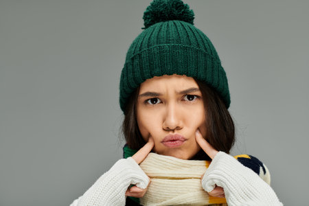 A young woman in winter clothing showcases her emotions with a playful pout and stylish accessories.の写真素材