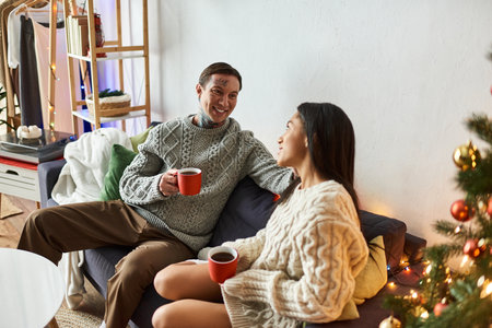 A couple enjoys warm beverages together, surrounded by festive decorations and holiday cheer.の写真素材