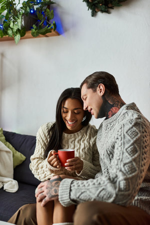 A couple cuddles together, sharing warmth and joy over hot cocoa in a festive atmosphere.の写真素材