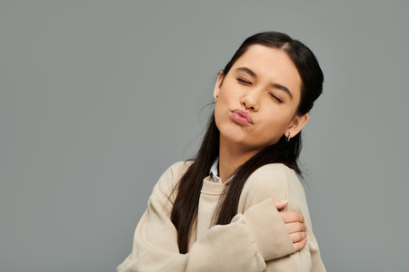 A young woman playfully poses, conveying emotions with a charming expression and fashionable outfit.の写真素材