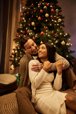 A couple shares joyful moments at home, embracing amidst festive decorations and holiday spirit.の写真素材