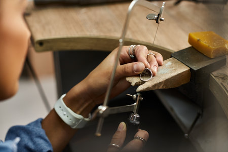 A talented woman focuses on creating a beautiful ring, showcasing her expertise with jewels.の写真素材