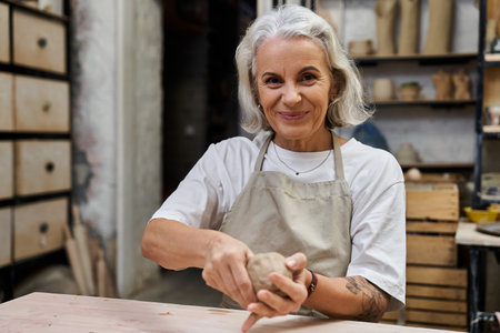 A talented mature woman works diligently with clay, showcasing her artistic skills in pottery.