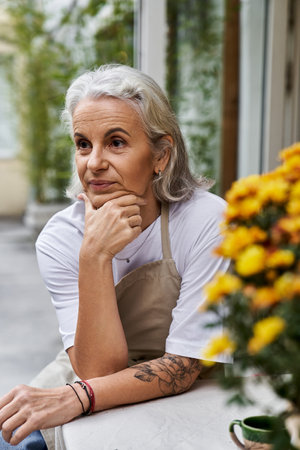 A thoughtful woman sits gracefully outdoors, appreciating the beauty of cheerful blooms.