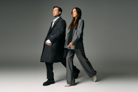 A young couple showcases contemporary fashion while walking together in a studio setting.の写真素材