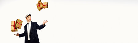 A stylish man dressed in holiday fashion playfully juggles beautifully wrapped Christmas presents, embodying the joy and excitement of the festive season in 2025.の写真素材