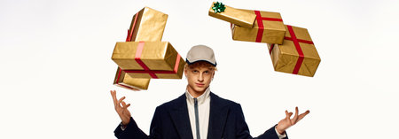 A fashionable man expertly juggles beautifully wrapped gift boxes adorned with red ribbons, creating a festive atmosphere.の写真素材