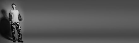 A stylish man showcases contemporary holiday fashion with a cozy knit sweater and vibrant patterned pants.の写真素材