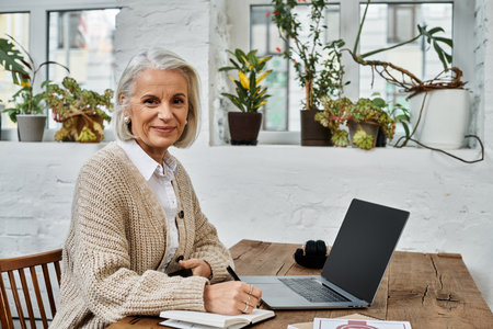 A graceful mature woman takes notes while enjoying the tranquil atmosphere of her workspace.