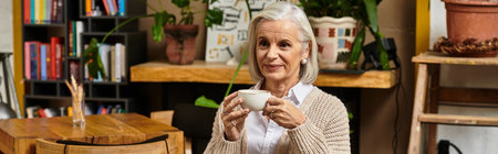 A beautiful woman with gray hair sips her drink while relaxing in a charming environment.の写真素材