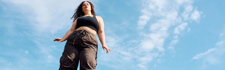A confident plus size woman embraces natures beauty, standing in a sun drenched field.の写真素材