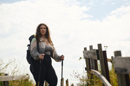 A confident plus size woman walks through a lush field, enjoying the beauty of nature.の写真素材