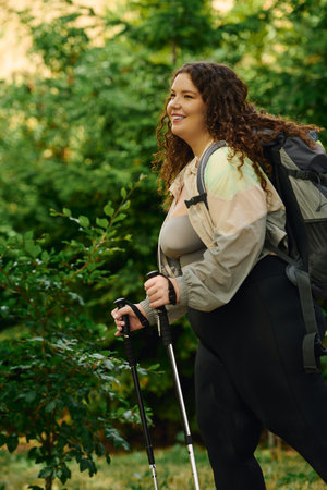 A joyful plus size woman walks through a vibrant nature forest, enjoying her outdoor adventure.の写真素材