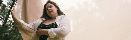 A plus size woman stands elegantly in a vibrant field, embracing the beauty of nature.