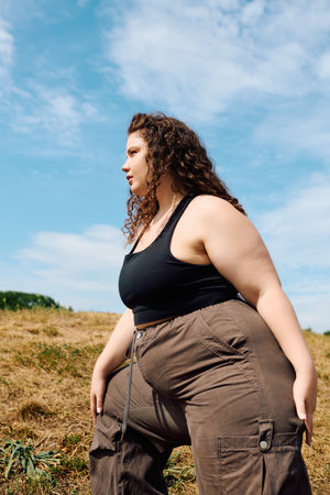 The radiant plus size woman stands gracefully in a lush field, embracing the beauty of nature.の写真素材