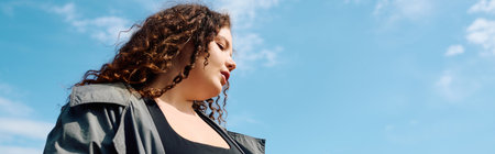 A confident plus size woman stands amidst a vibrant field under a bright blue sky, radiating joy.