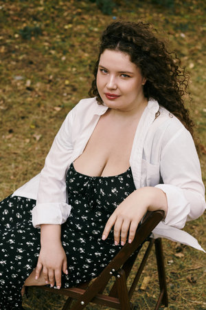 A plus size woman relaxes in a serene field, embracing the beauty of nature around her.の写真素材