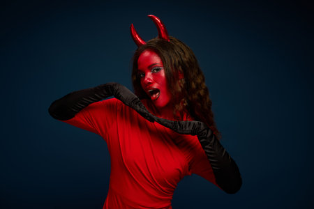 A stunning woman displays her vibrant red Halloween costume and striking accessories.