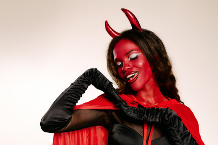 This stunning woman showcases her devil costume, featuring playful horns and a bold cape.の写真素材