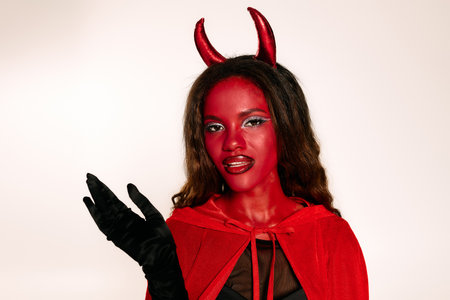 A striking woman in a devil costume embraces the Halloween spirit at a lively gathering.
