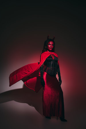 A captivating woman embraces Halloween spirit in a striking red costume, exuding confidence.
