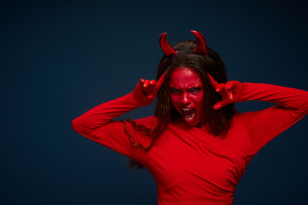 A captivating woman dressed as a devil passionately expresses excitement for Halloween.