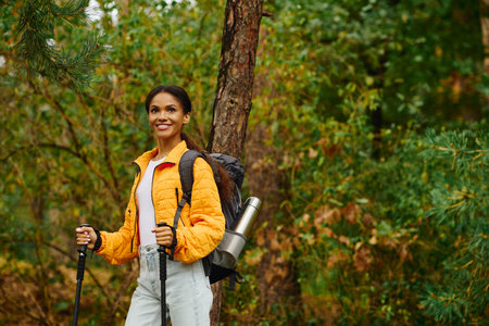 Under the golden hues of autumn, a young woman smiles as she explores the serene forest trails.の写真素材