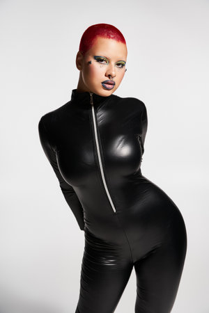 A young woman with pink hair and a striking outfit expresses her bold fashion sense in a creative environment.の写真素材