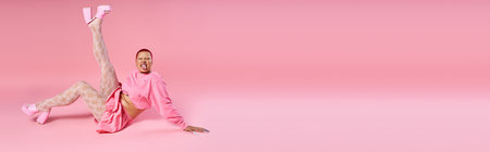 A confident young woman with striking pink hair showcases her unique fashion in a playful studio atmosphere.の写真素材