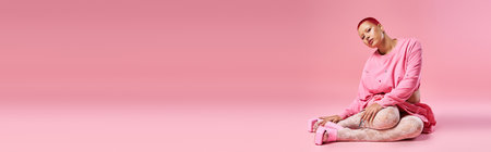 A young woman with striking pink hair and a nose piercing confidently displays her bold fashion choices.の写真素材