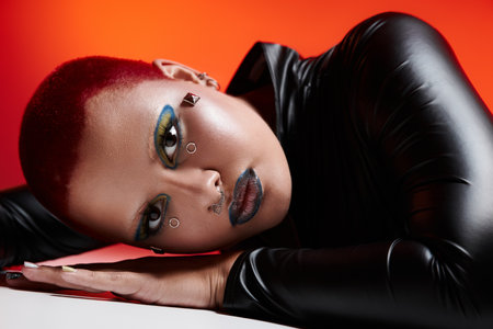 The young woman flaunts her bold, colorful style with pink hair, dramatic makeup, and expressive...