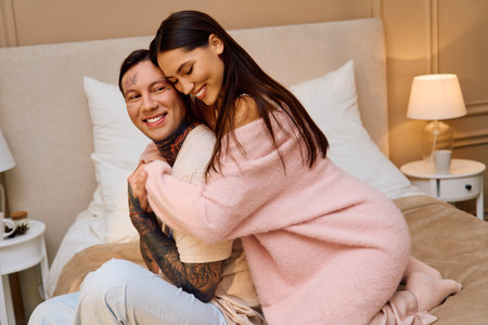 Man and woman enjoy a tender moment together, laughing and embracing in a softly lit room.の写真素材