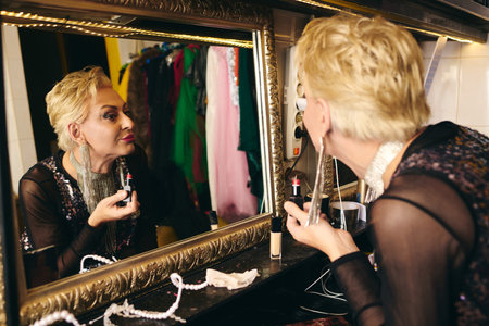 A drag queen meticulously applies makeup in a dressing room, ready for a holiday show.の写真素材