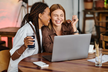 A happy moment unfolds as an African American woman shares a warm smile with her girlfriend at a bustling cafe.の写真素材
