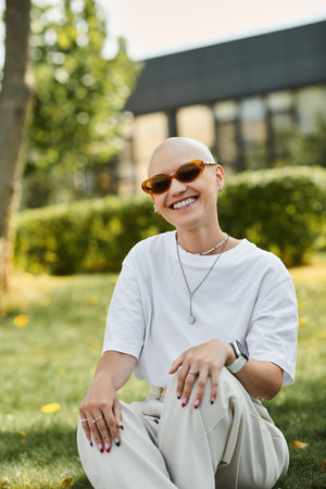 A young bald woman sits in a lush garden, radiating happiness while dressed elegantly.の写真素材