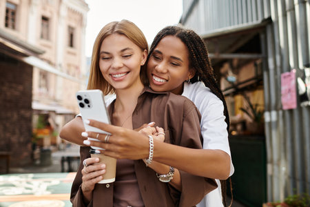 A happy African American woman with braided hair embraces her girlfriend, sharing smiles.の写真素材