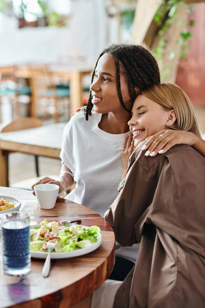 A happy multicultural couple shares a tender moment at a cafe, savoring tasty dishes and each others company.の写真素材