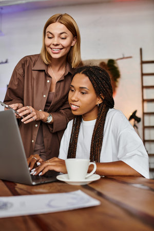 A joyful couple shares laughter and love over coffee while working on a laptop in a cozy cafe environment.の写真素材