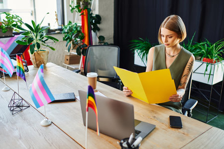 A focused individual reviews documents amidst an inclusive environment filled with pride flags.の写真素材