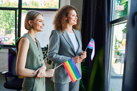 Coworkers bond and celebrate their pride, holding flags while enjoying sunny office views.の写真素材