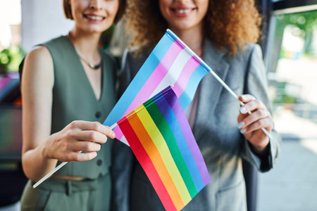 Two coworkers joyfully display pride flags, symbolizing inclusivity and support at work.の写真素材