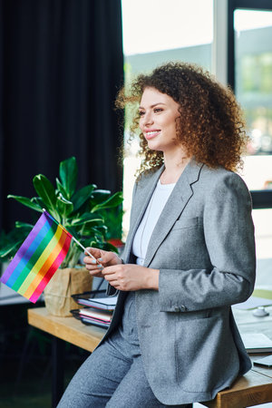 A confident person proudly waves a rainbow flag, supporting the LGBT community at work.の写真素材