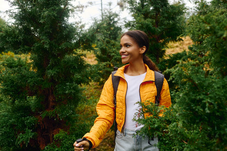 A joyful young woman explores a colorful autumn forest, surrounded by lush greenery and vibrant foliage.の写真素材