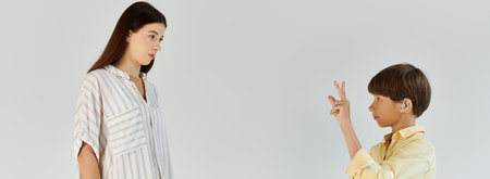 A mother observes her son with hearing impairment as he communicates using sign language.の写真素材