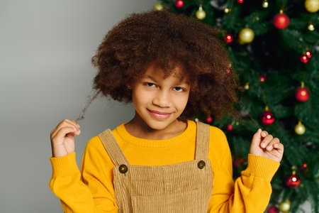 Cheerful girl poses by a decorated Christmas tree with joy and warmth in 2025.