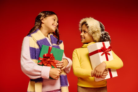 Two joyful girls share smiles and holiday gifts, embodying the spirit of Christmas 2025.の写真素材