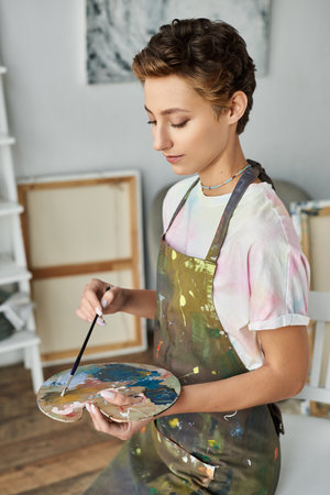Inside her cozy home, a young woman expresses her creativity by painting a vibrant picture with passion.の写真素材