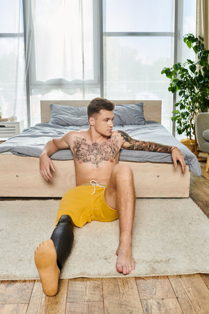 A young man sits on the floor, showcasing his unique style and strength with a prosthetic leg.