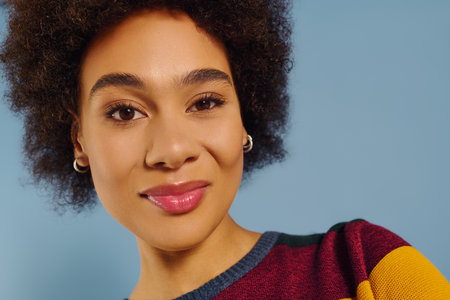 A young woman with curly hair radiates joy and confidence, dressed in colorful attire.の写真素材