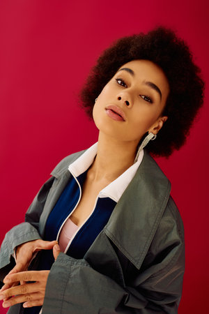 The young woman gazes thoughtfully, her expressive features captured against a bold pink setting.の写真素材